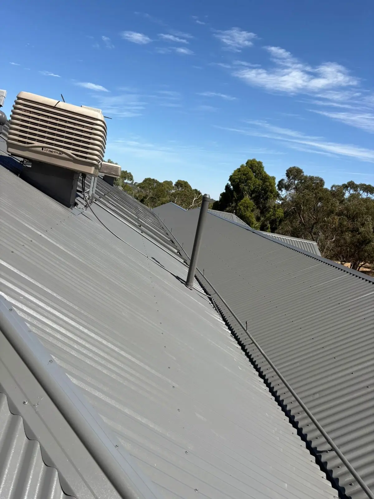 New grey metal roof planes with evaporative cooler